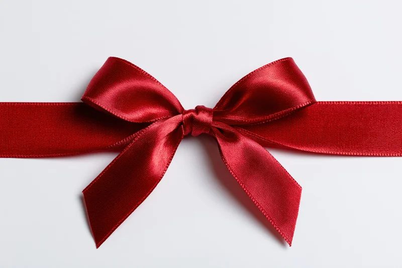 Red satin ribbon tied in a bow across a white background