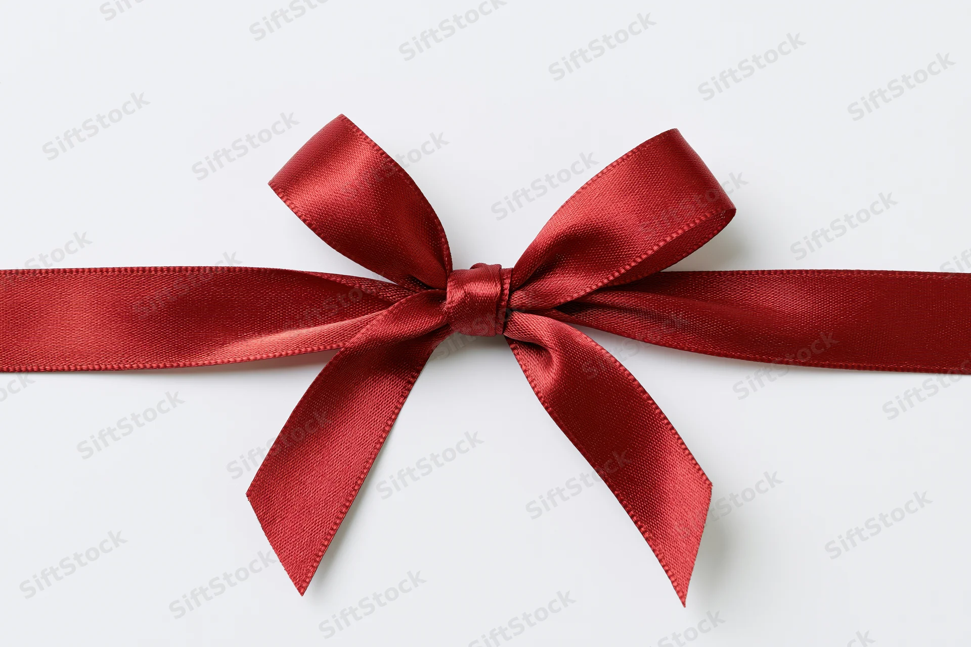 Red satin ribbon tied in a bow across a white background