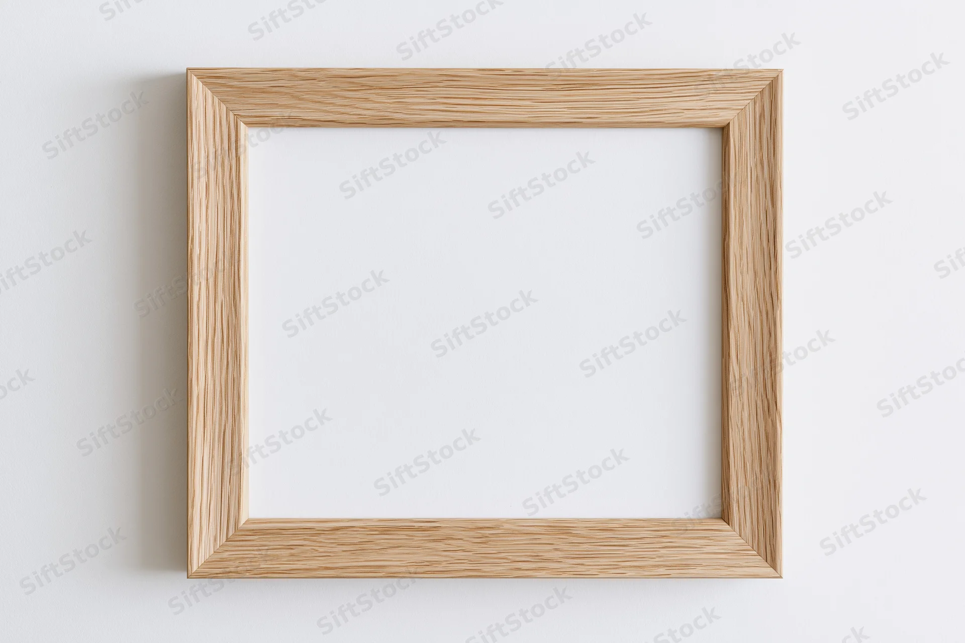 Light oak wooden picture frame hanging on white wall with empty center for display
