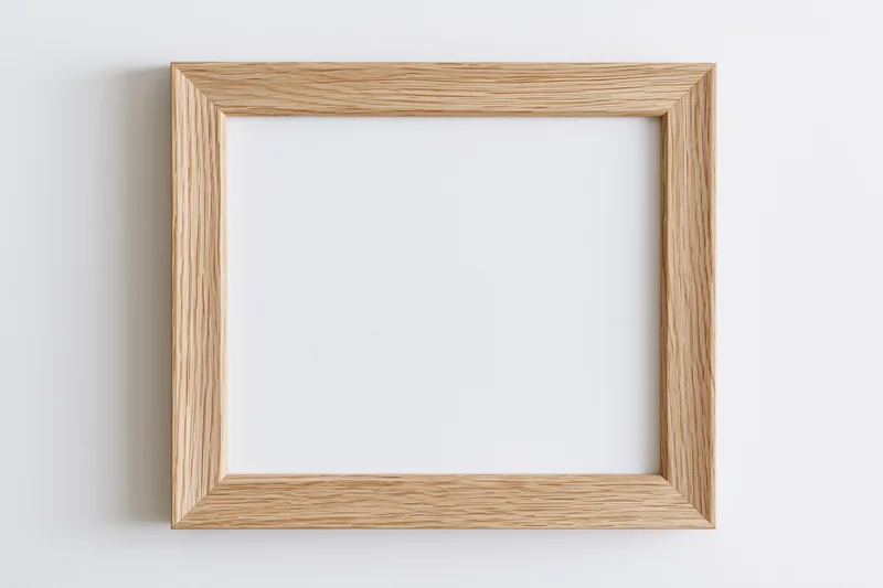 Light oak wooden picture frame hanging on white wall with empty center for display