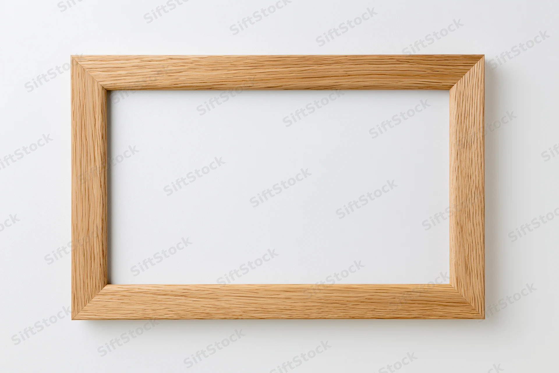 Light oak wooden picture frame hanging on white wall, empty and ready for display