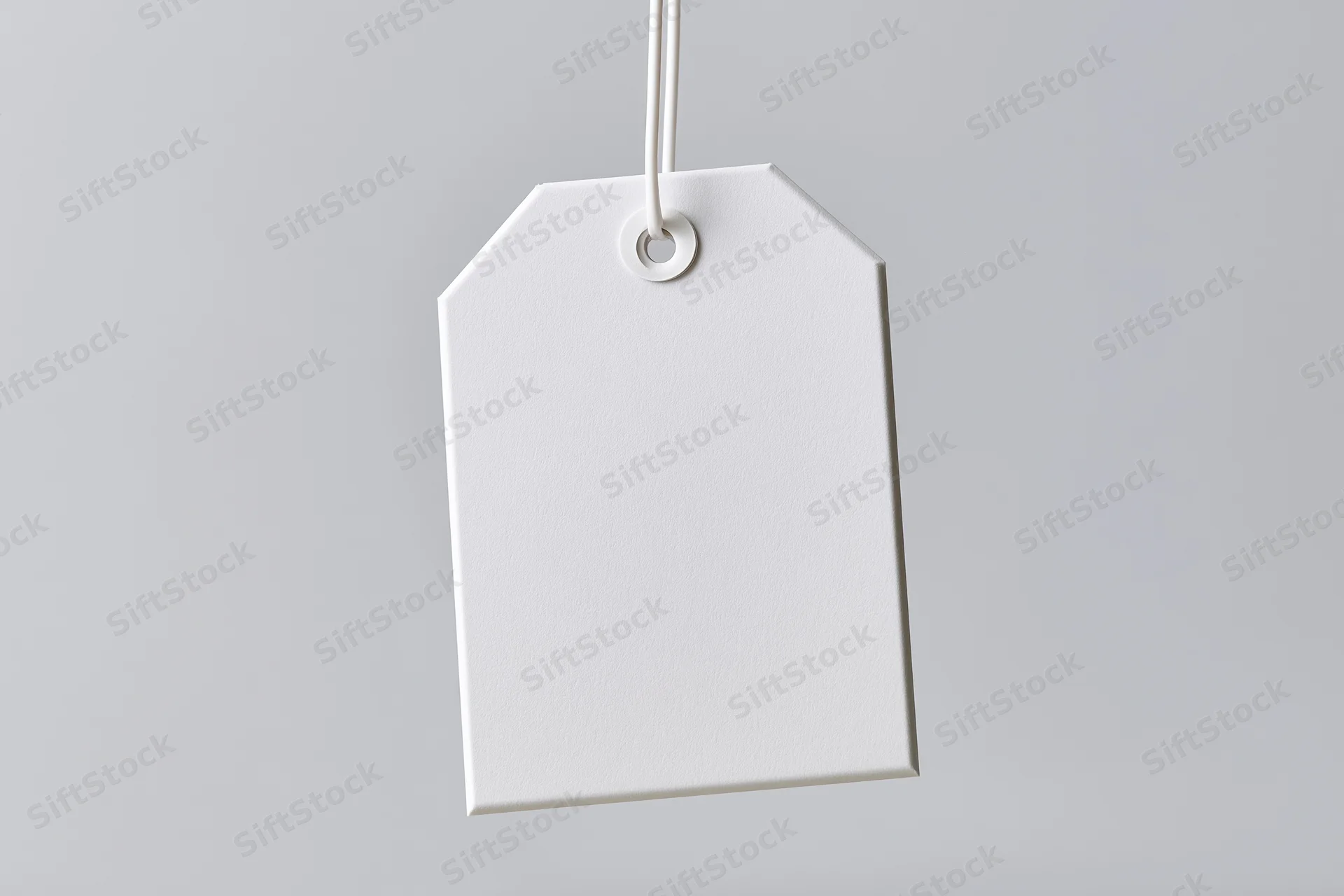 Blank white paper tag hanging from string against gray background