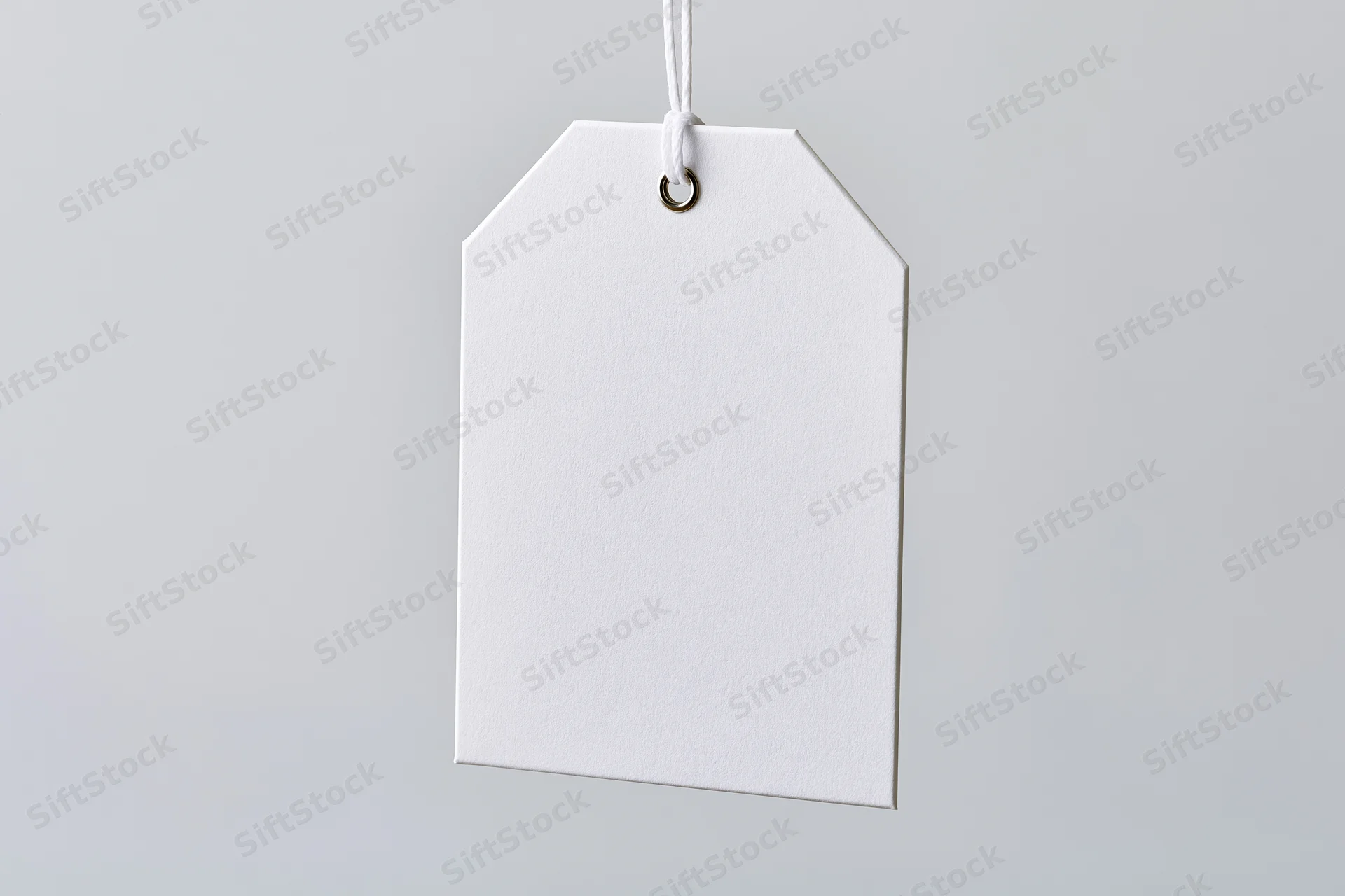 Blank white paper tag hanging from string against plain background