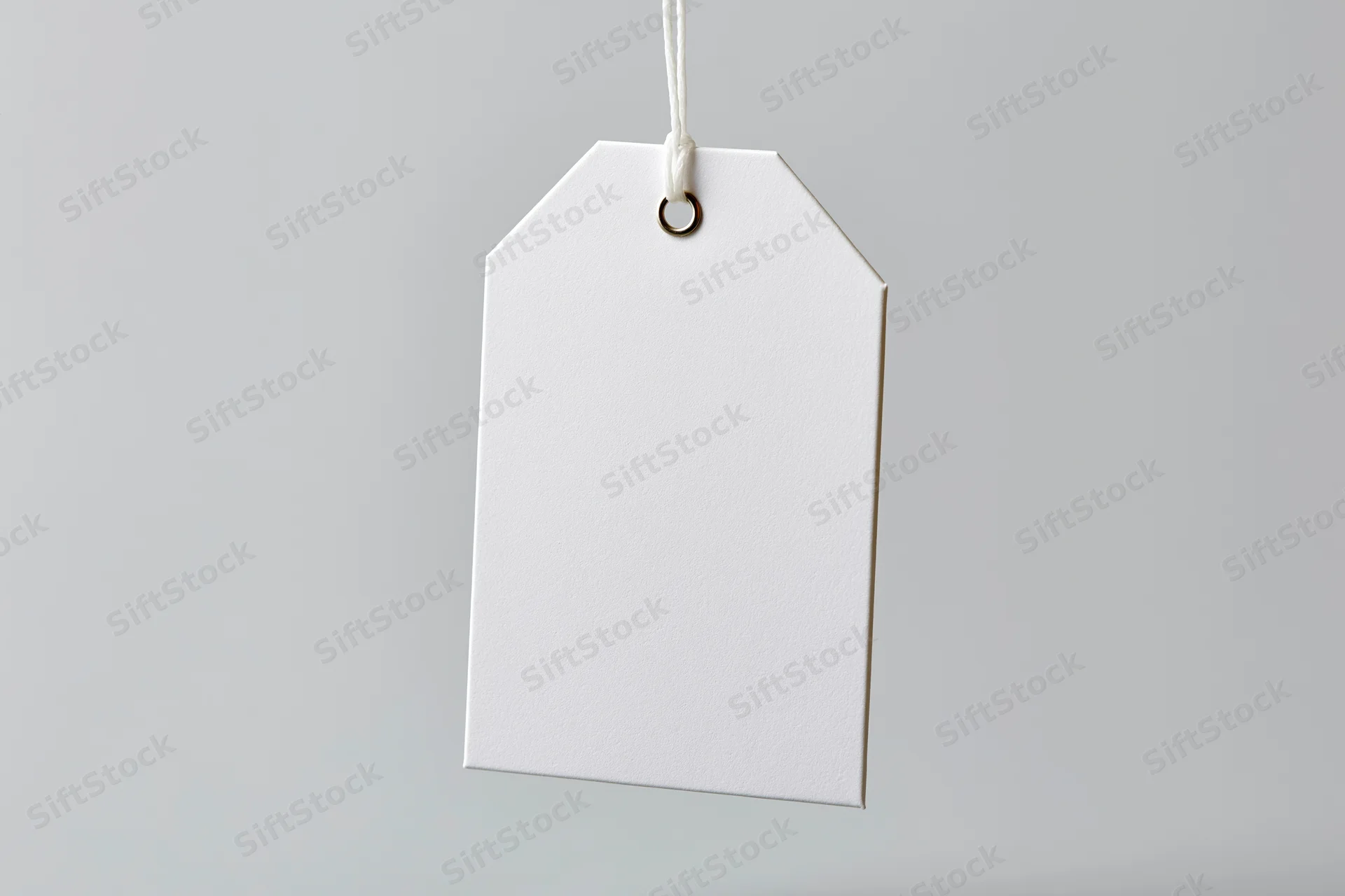 Blank white paper tag hanging from string against plain background