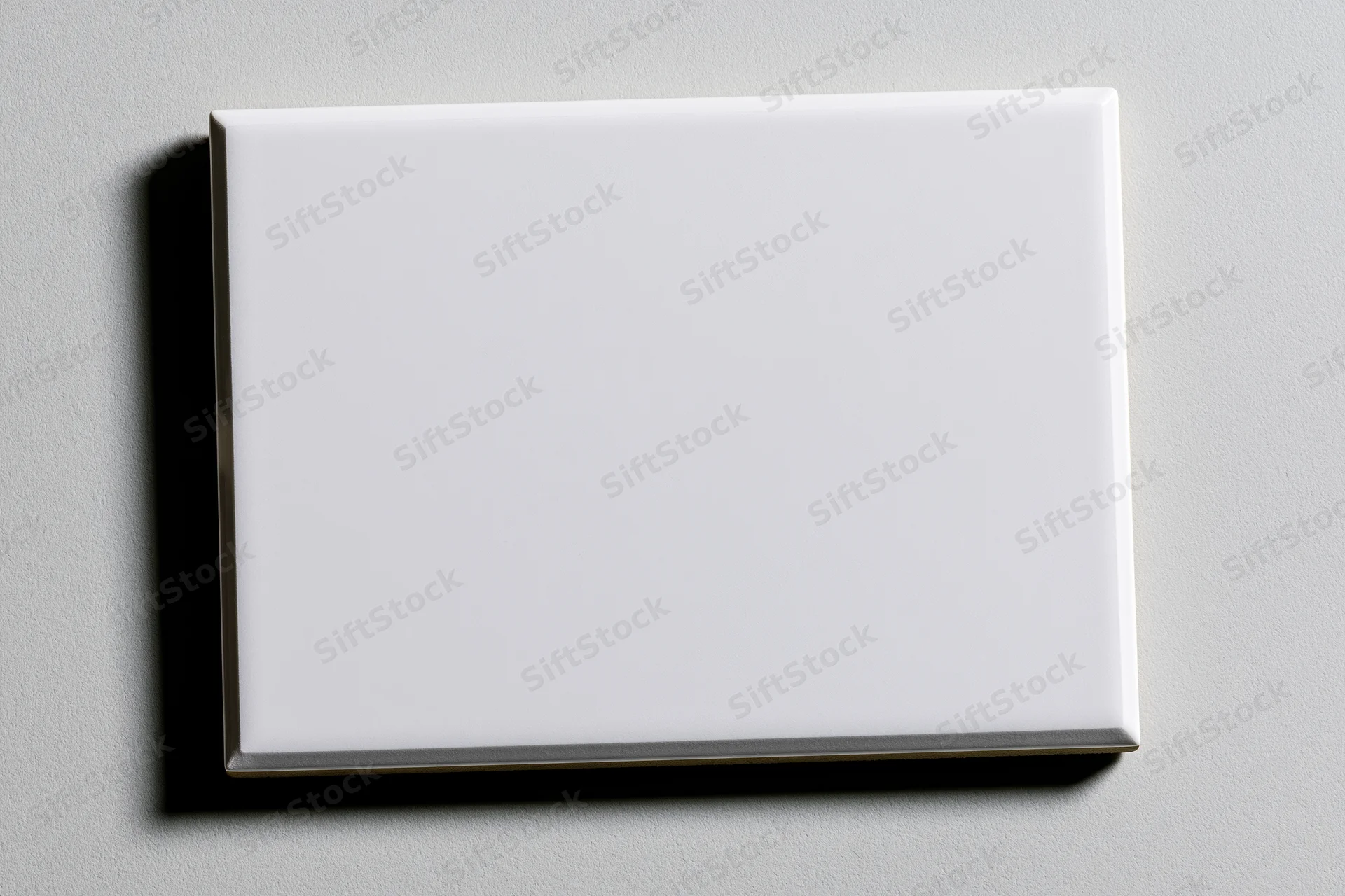 Blank white rectangular glass tile mounted on a light gray wall