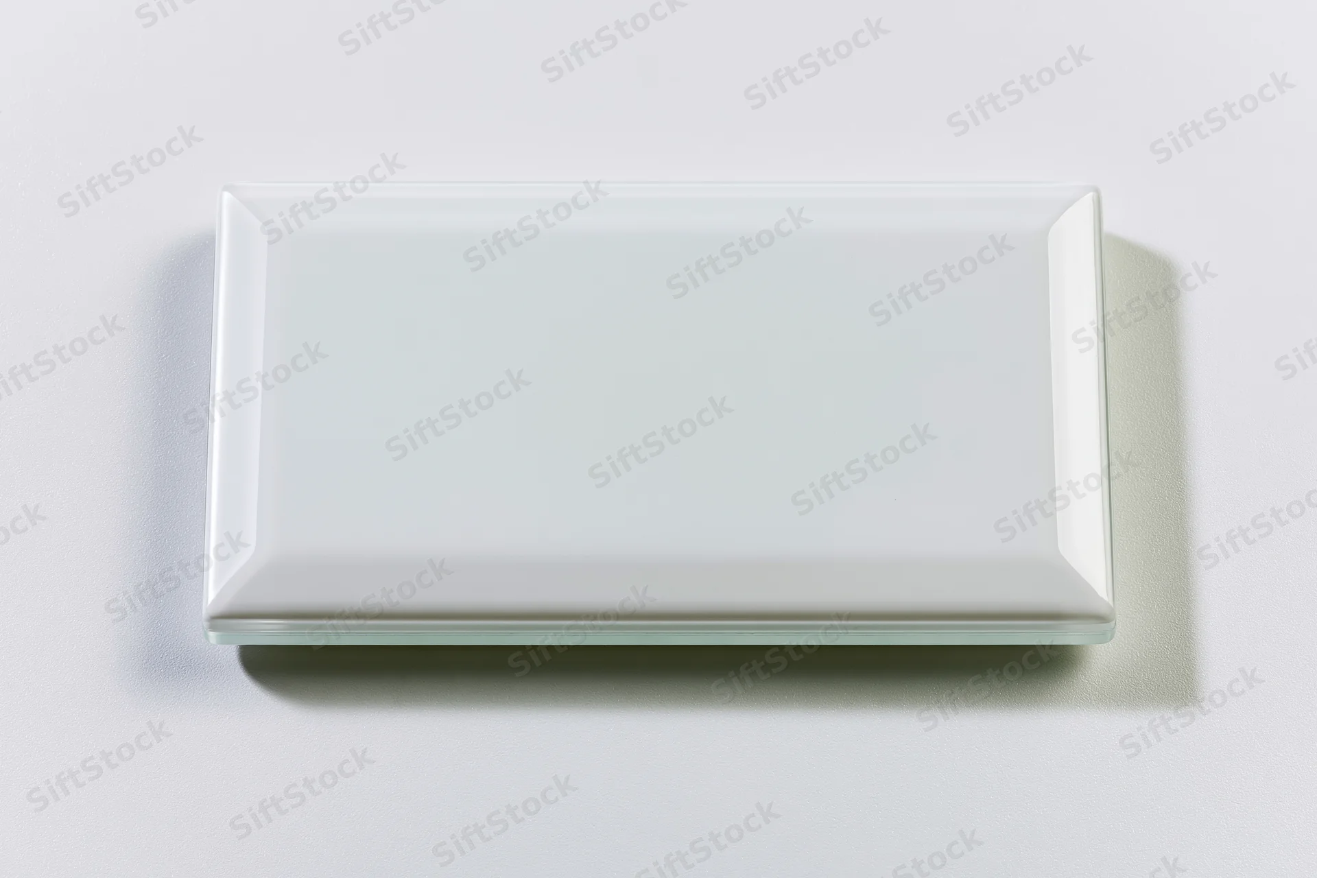Blank white rectangular glass tile lying flat on a plain surface