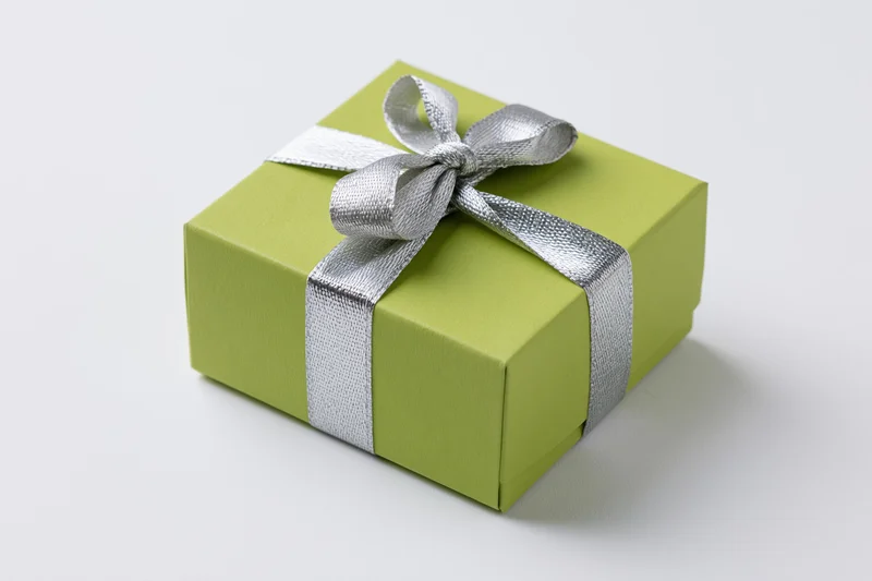 Green gift box wrapped with silver ribbon and bow on white background