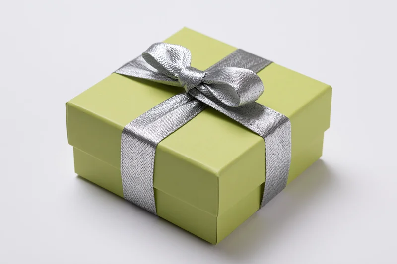 Lime green gift box with silver ribbon and bow on white background