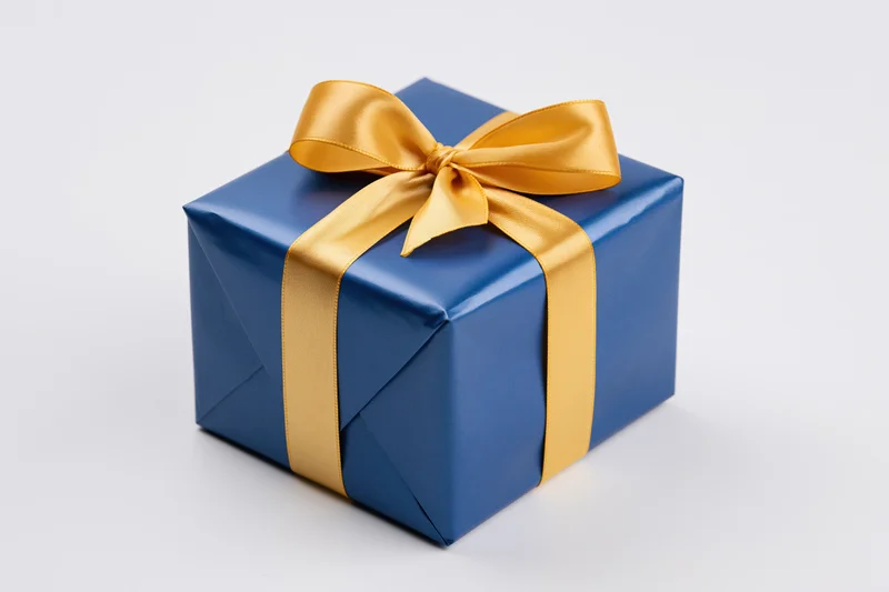 Blue gift box wrapped in glossy paper with gold satin ribbon bow on white background