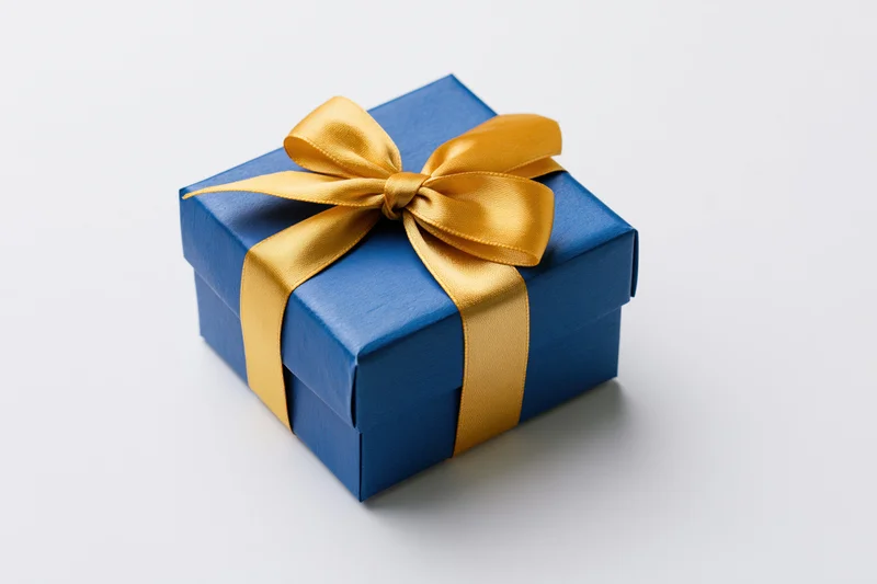 Blue gift box wrapped with gold ribbon on white background