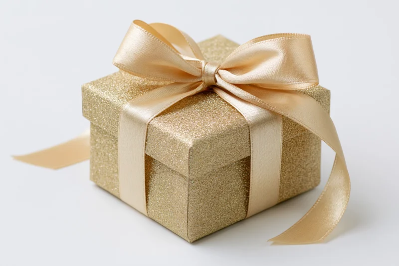 Gold glitter gift box with satin ribbon bow on white background