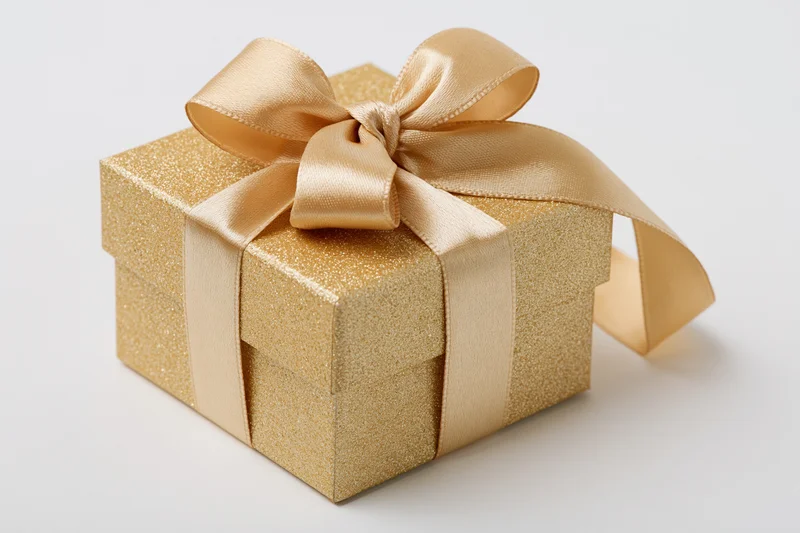 Gold glitter gift box with satin ribbon bow on white background