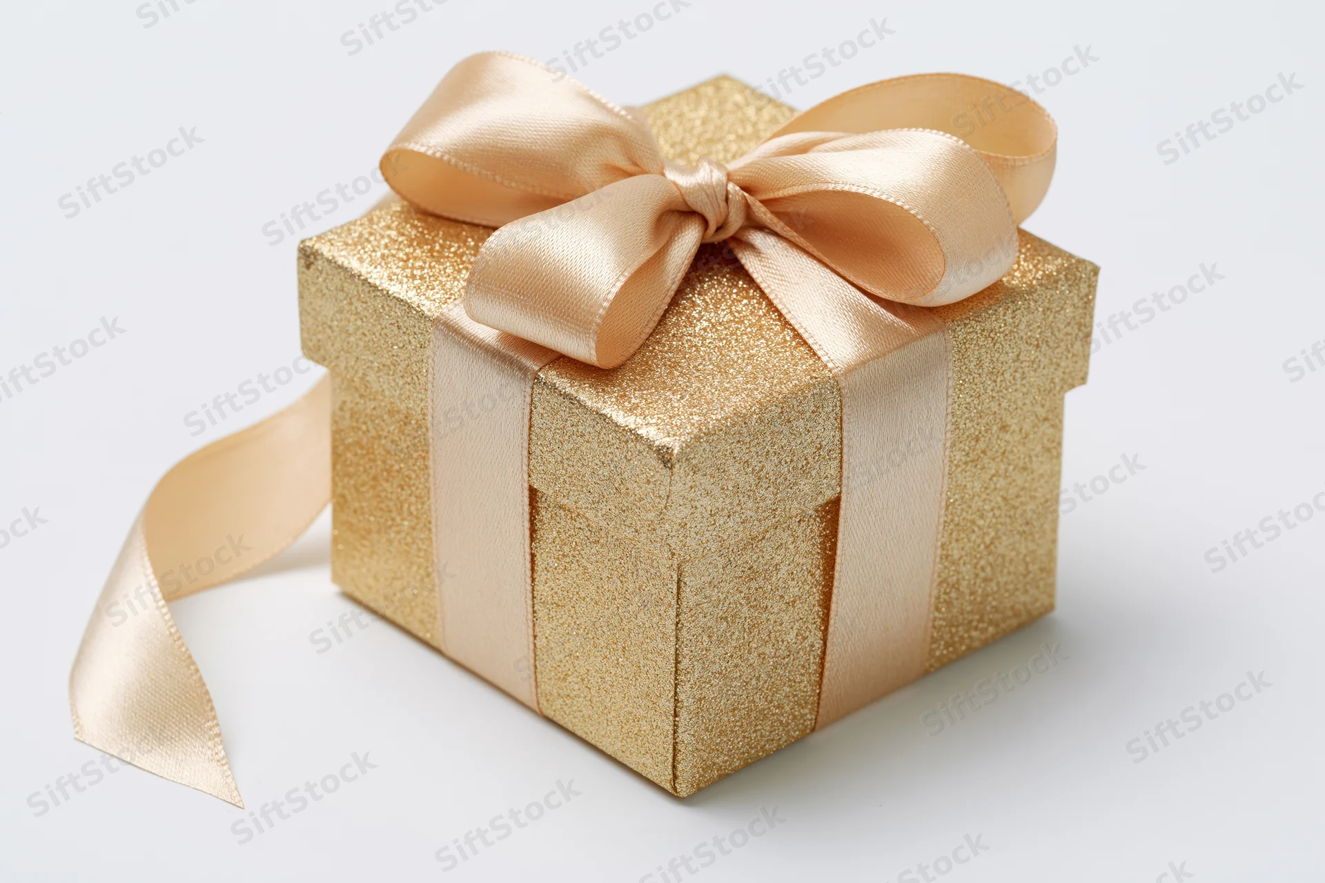 Gold glitter gift box with satin ribbon bow on white background