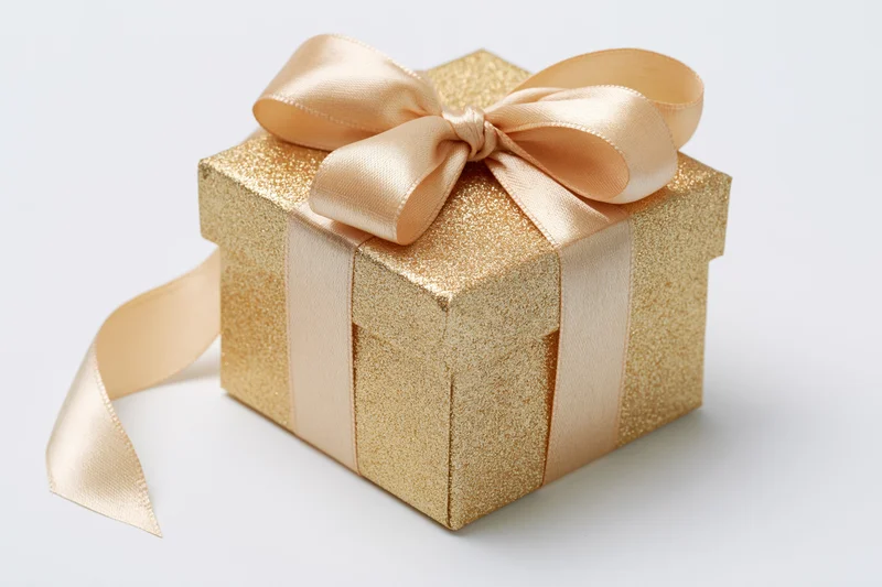 Gold glitter gift box with satin ribbon bow on white background