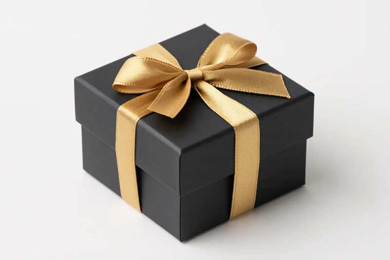 Matte black square gift box wrapped with gold satin ribbon on white background