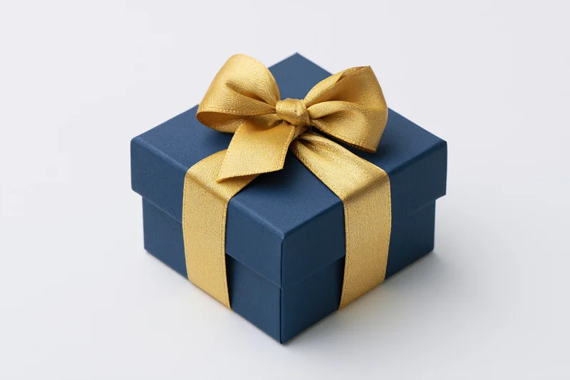 Navy blue gift box with gold satin ribbon bow on white background
