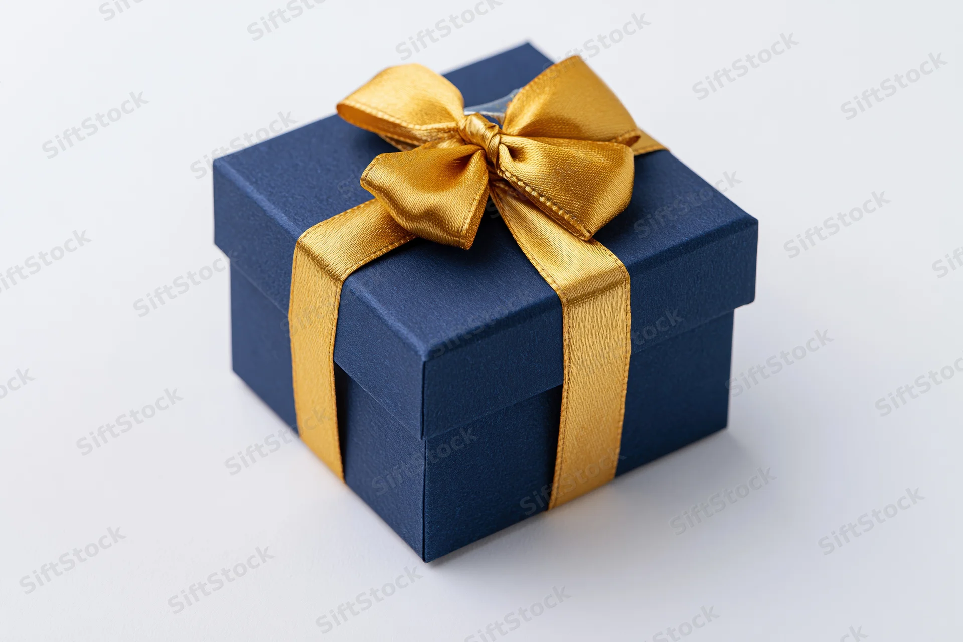 Navy blue gift box with gold satin ribbon bow on white background