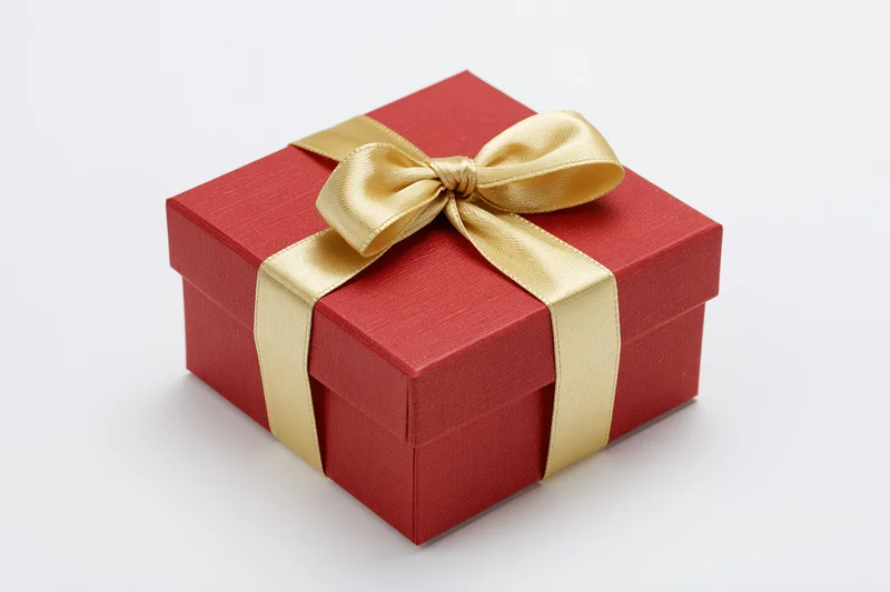 Red gift box wrapped with gold satin ribbon on white background