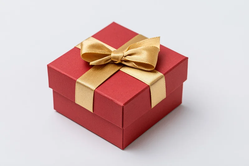 Red gift box wrapped with gold satin ribbon on white background