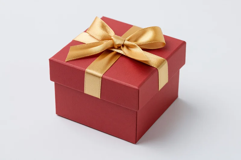 Red gift box wrapped with gold satin ribbon on white background