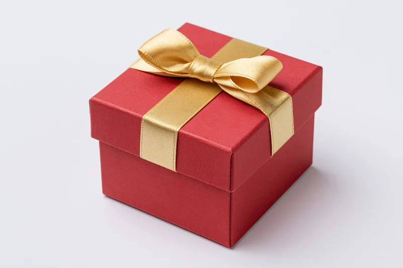 Red gift box wrapped with gold satin ribbon on white background