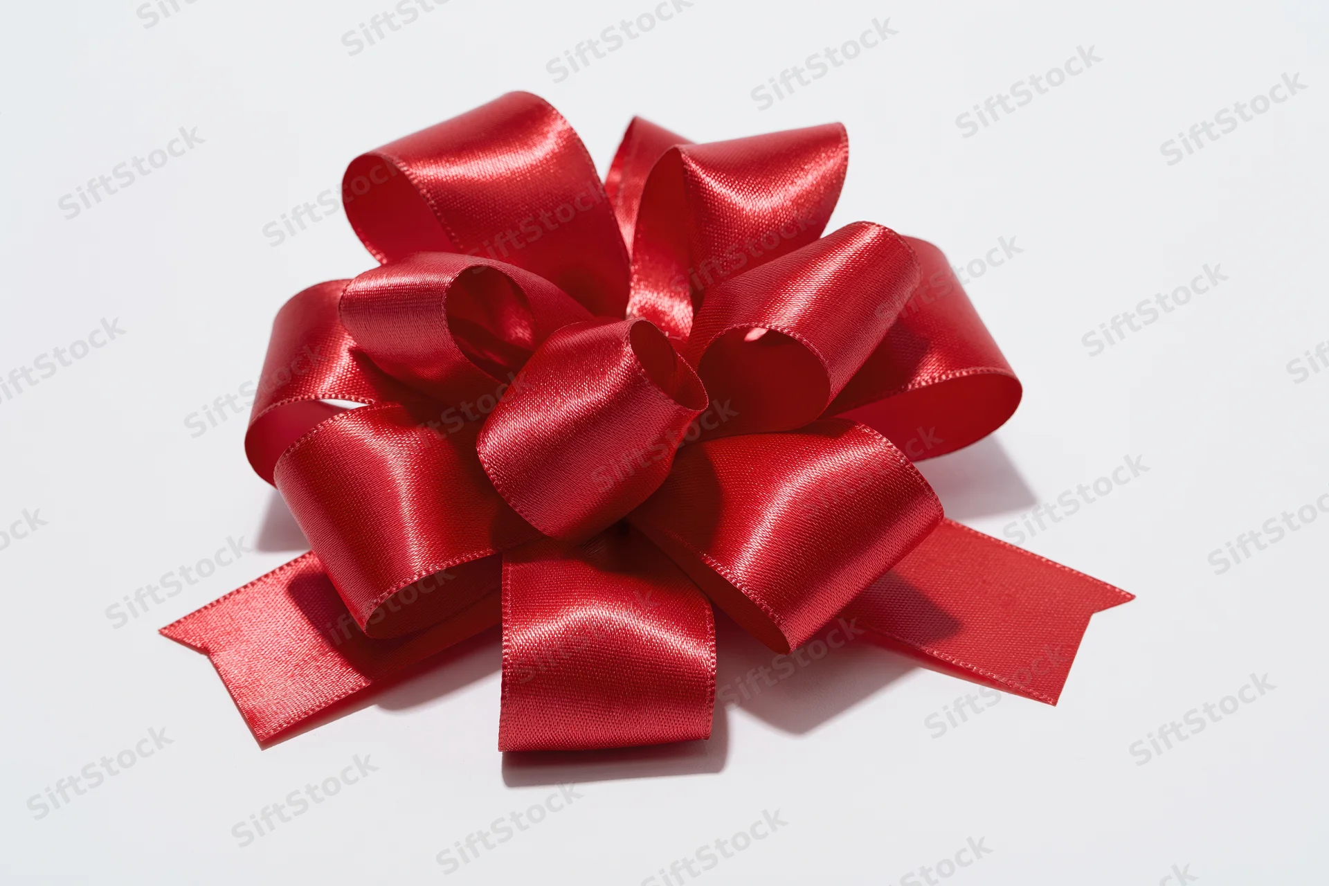Red satin gift bow with multiple loops on white background