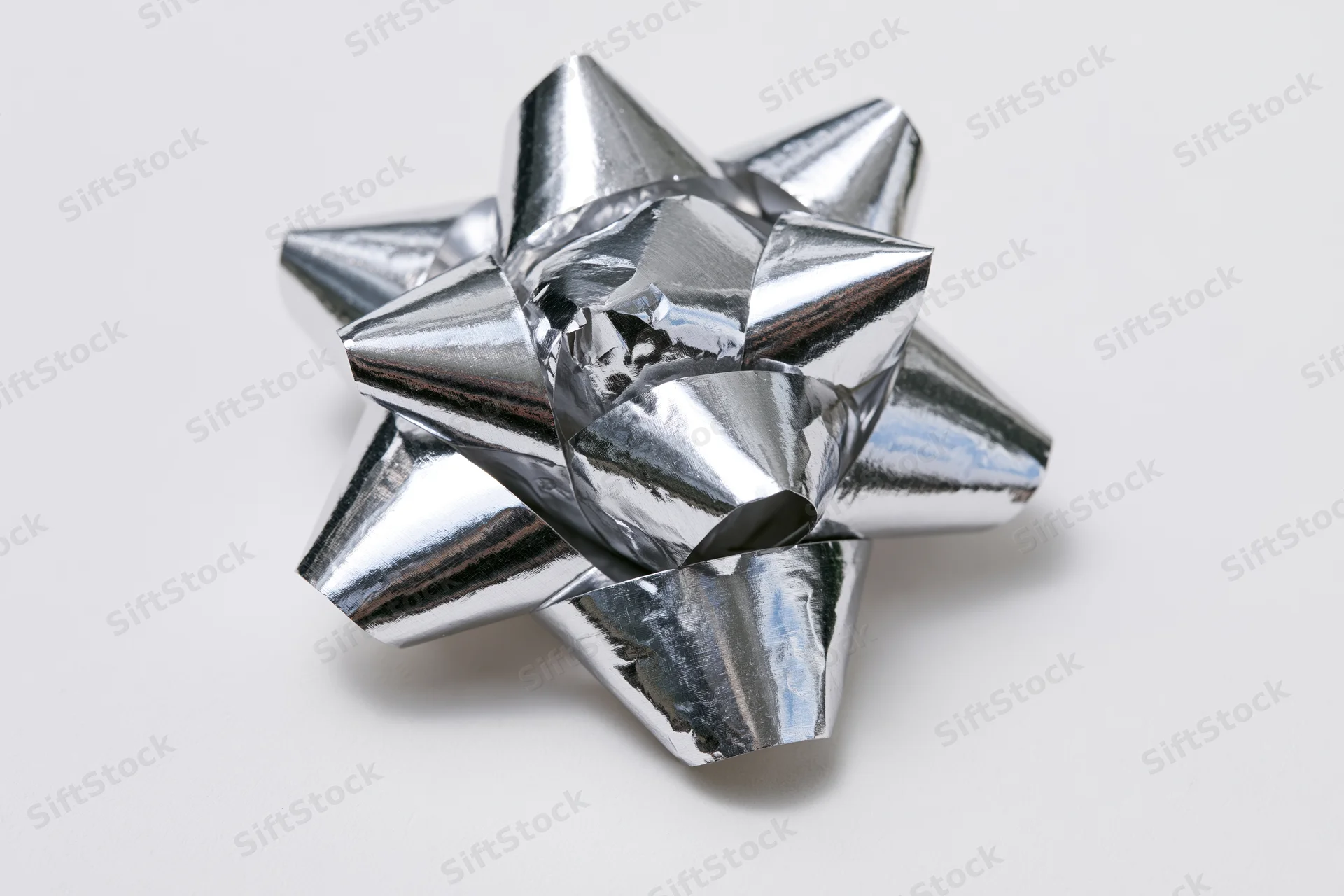 Silver metallic gift bow with layered foil loops on white background