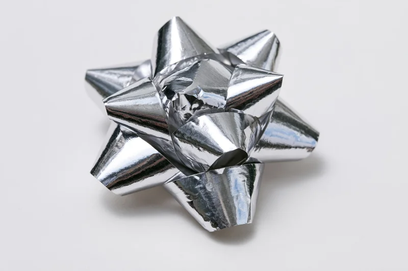 Silver metallic gift bow with layered foil loops on white background