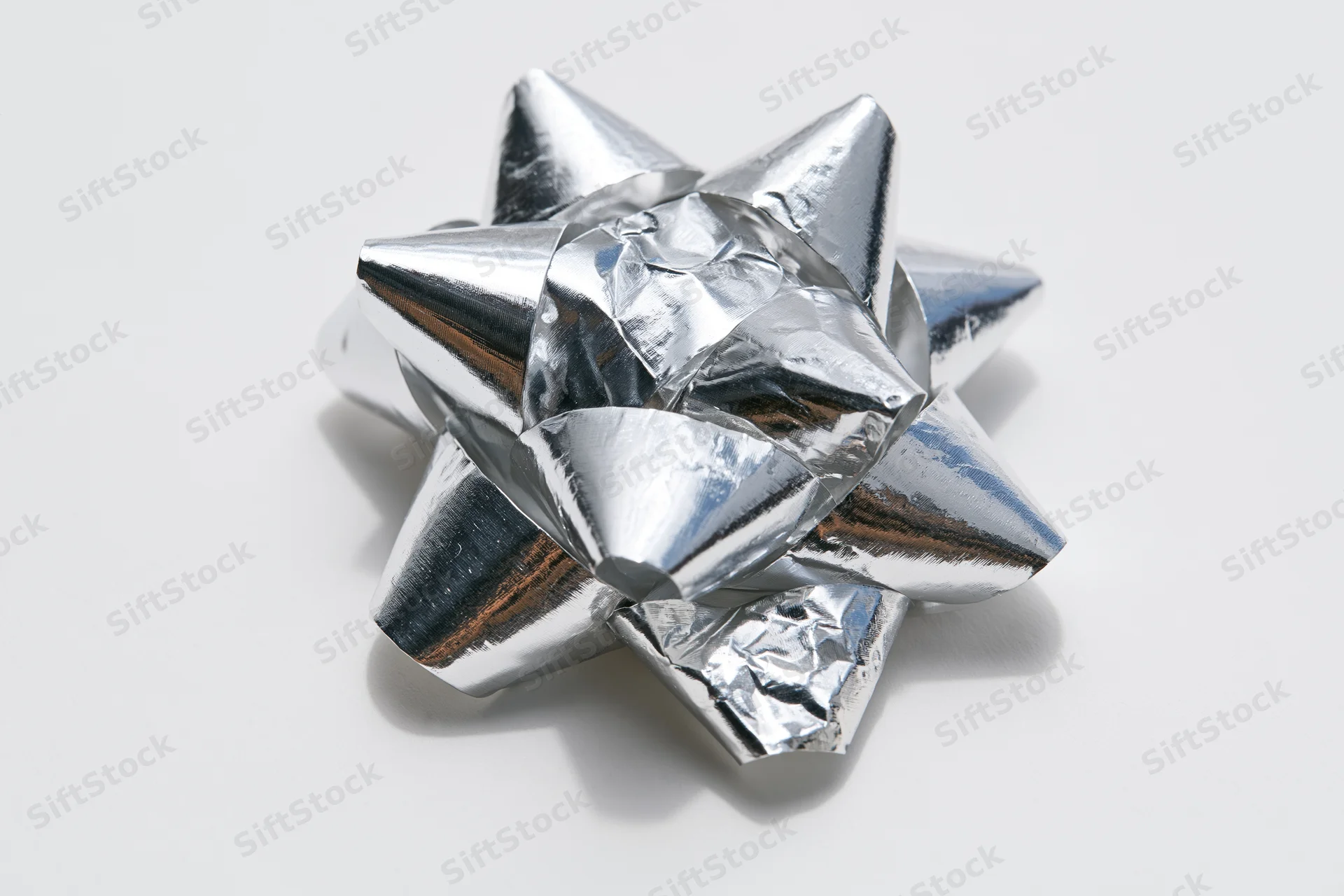 Silver metallic gift bow with layered foil loops on white background