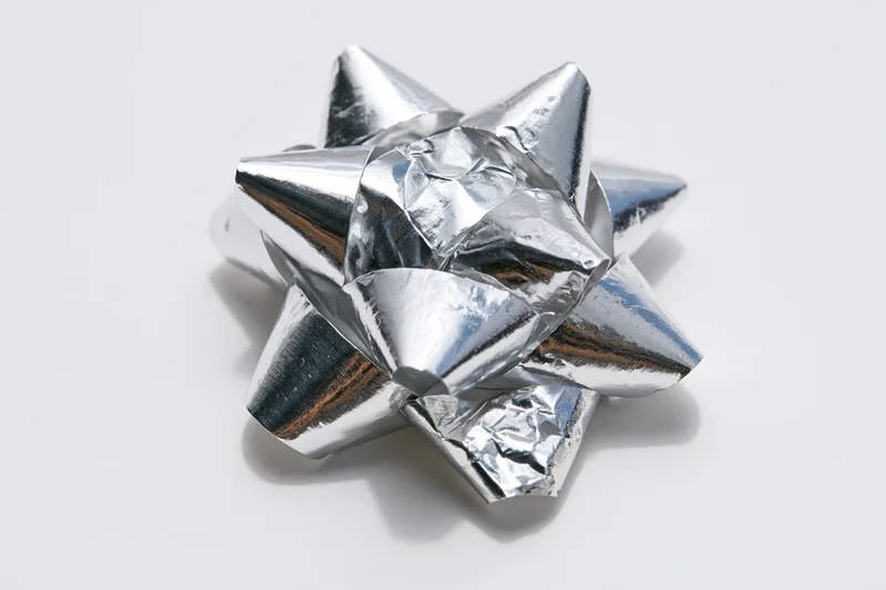 Silver metallic gift bow with layered foil loops on white background