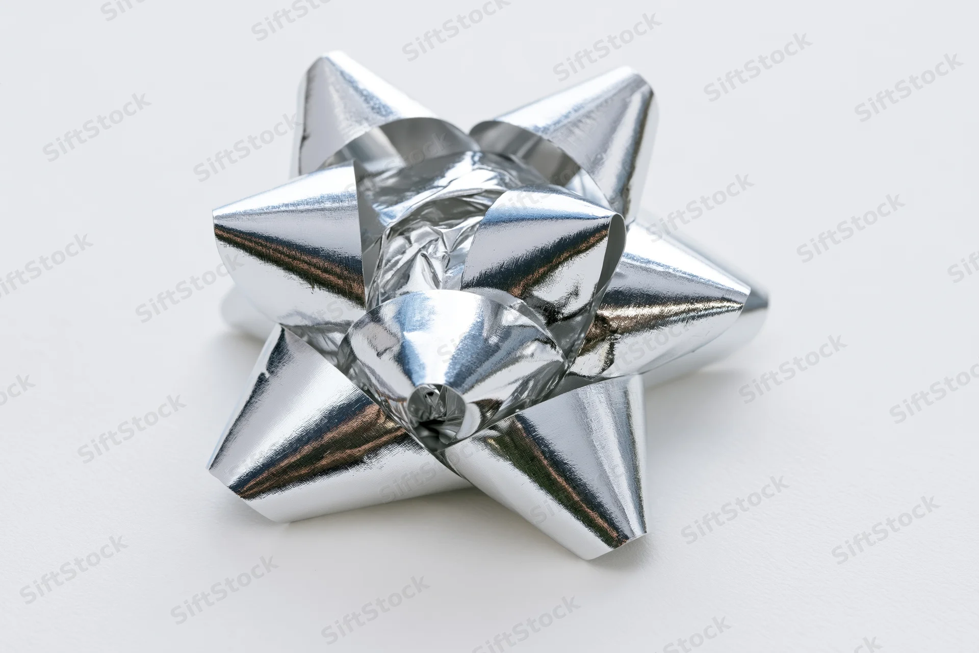 Silver metallic gift bow with layered foil loops on white background