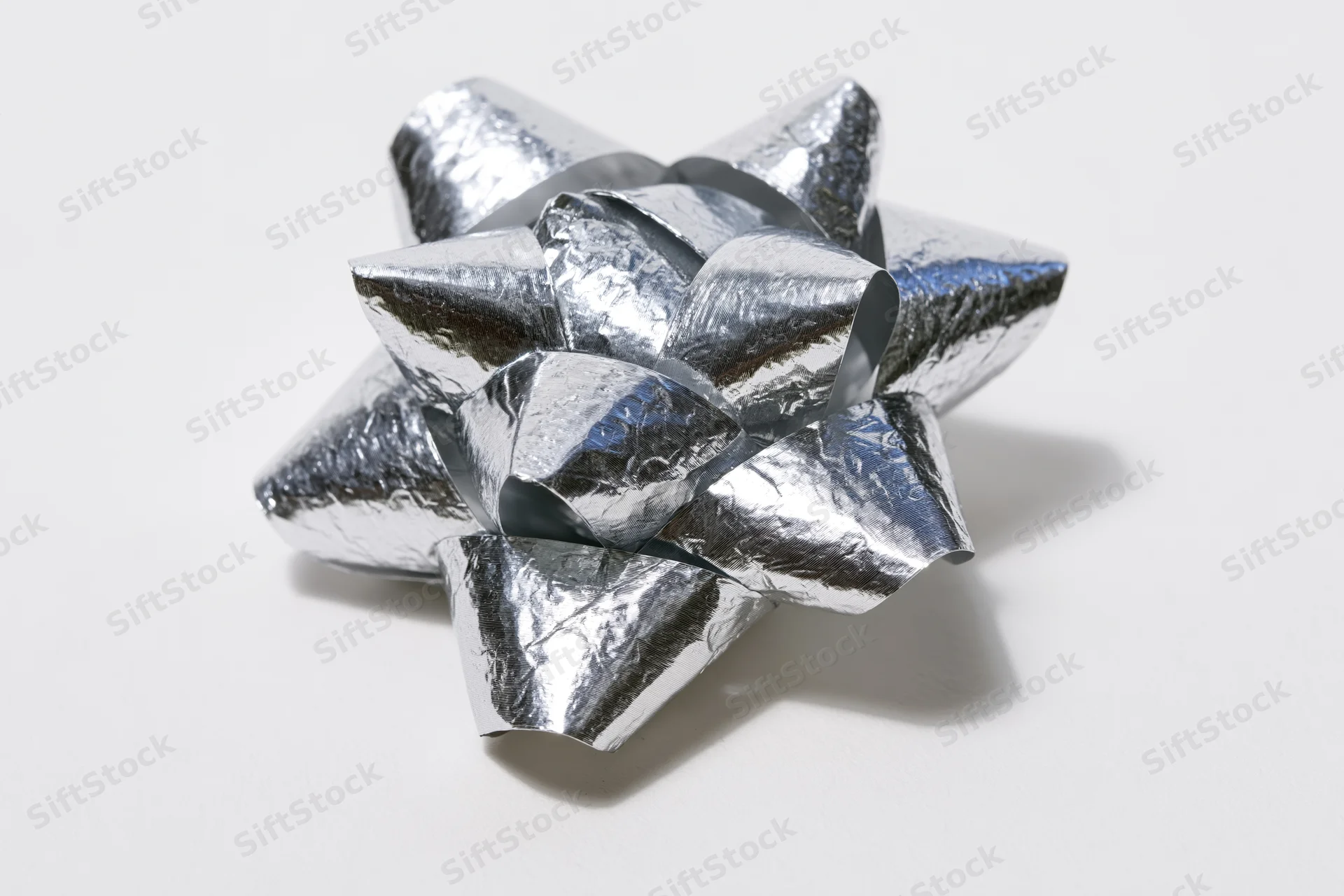 Silver metallic gift bow with layered foil loops on white background