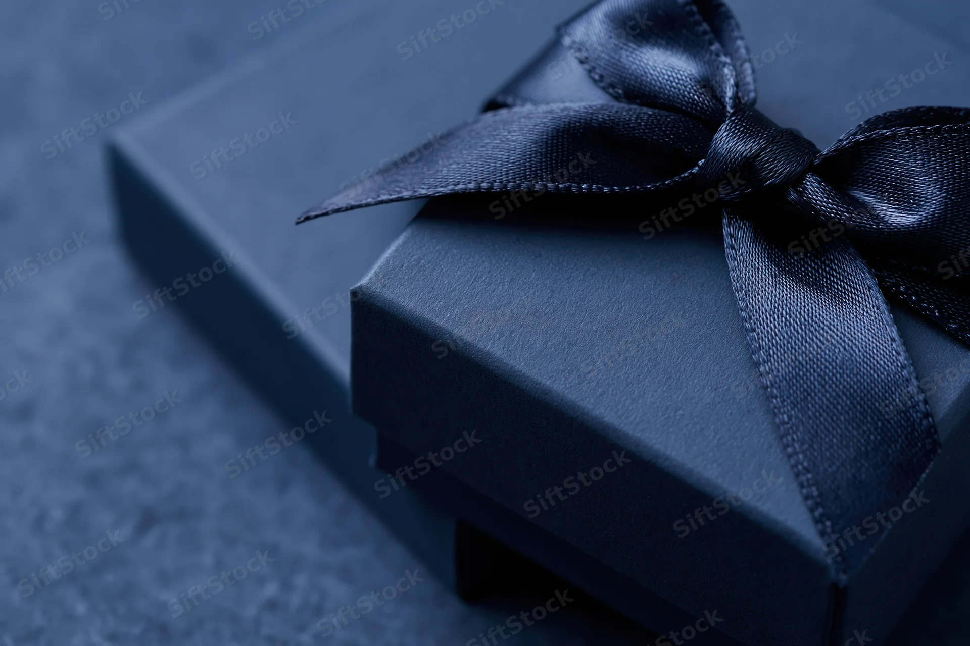 Navy gift box with satin grosgrain ribbon on textured surface