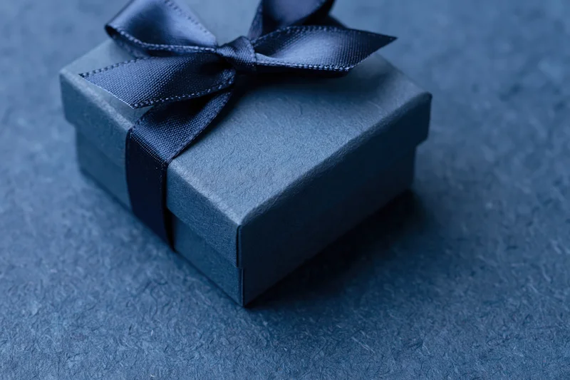 Navy gift box with satin grosgrain ribbon on textured surface