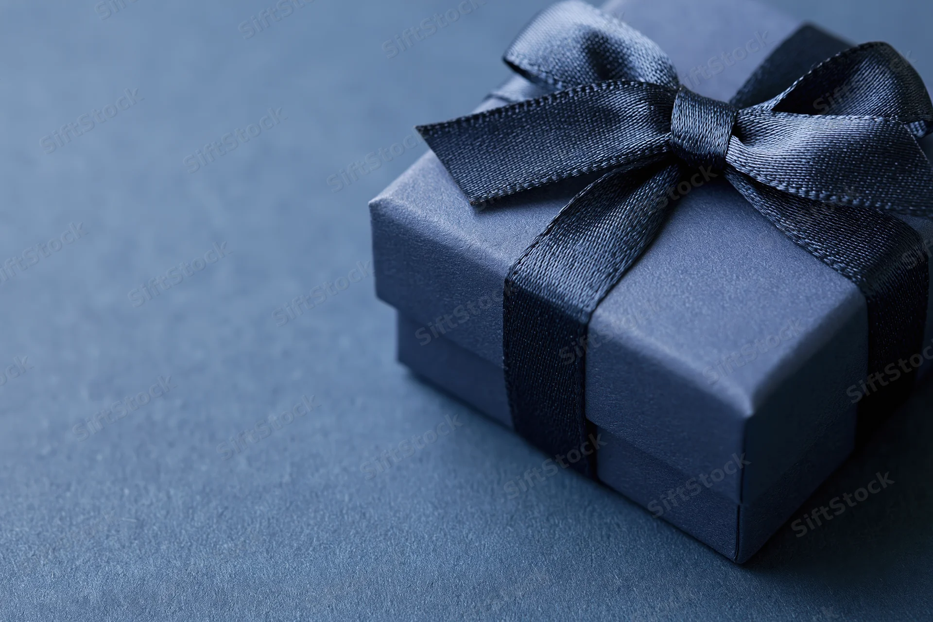 Navy gift box with satin grosgrain ribbon on textured blue surface