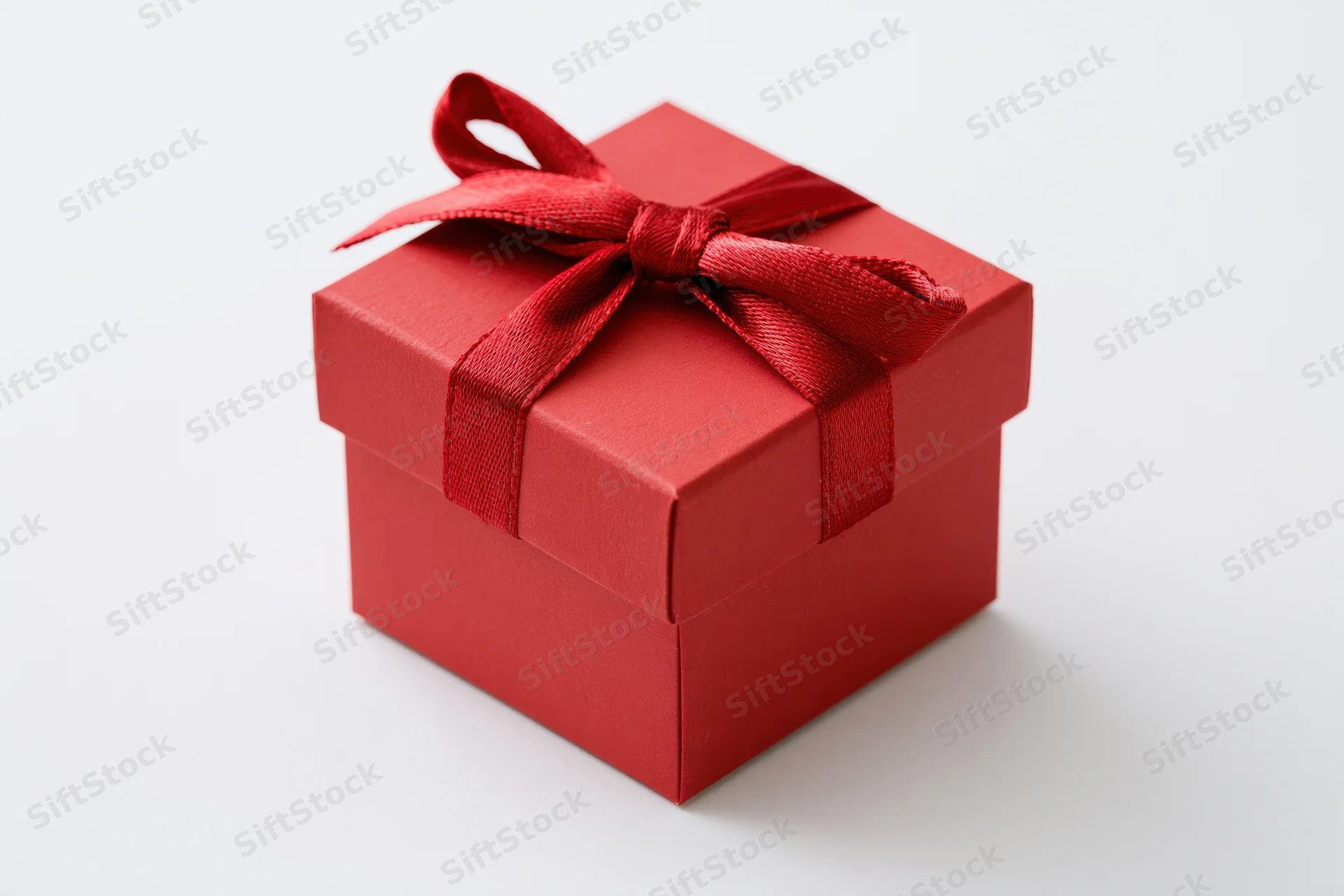 Small red gift box with ribbon bow on white background