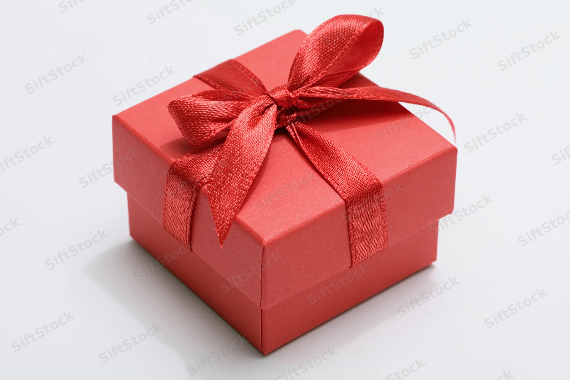 Small red gift box with satin ribbon bow on white background