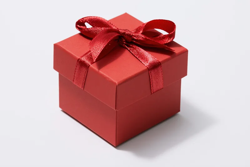 Small red gift box with ribbon bow on white background