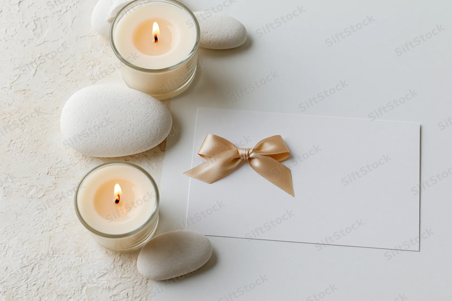 Spa gift card with champagne satin bow and candles on textured surface
