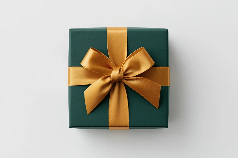 Square gift box wrapped in matte dark green paper with gold satin ribbon bow on white background