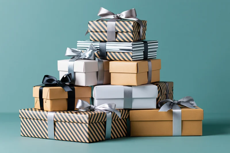 Stack of wrapped gift boxes arranged in a loose pile on a teal surface