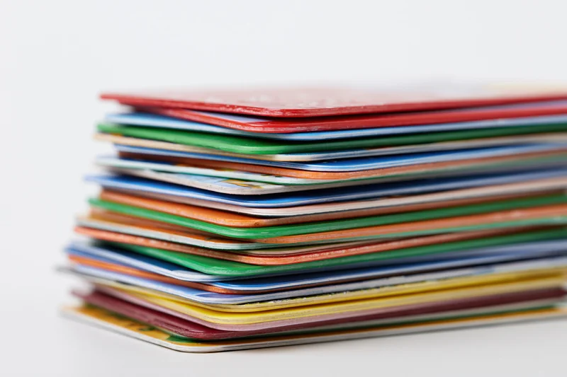 Tall stack of colorful plastic cards piled unevenly on white background