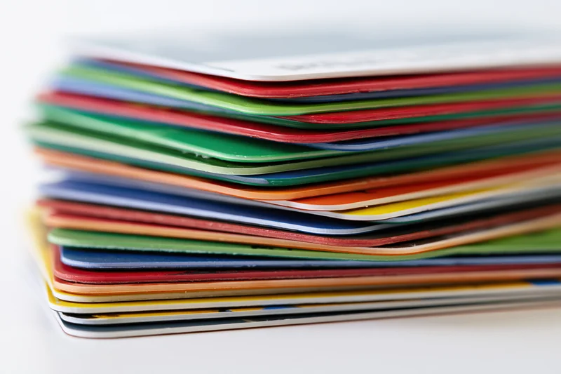 Tall stack of colorful plastic cards piled unevenly on white background