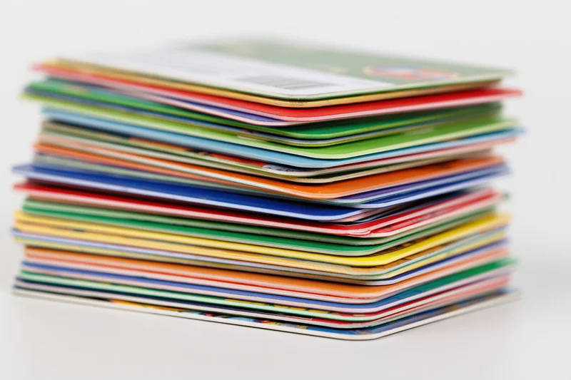 Tall stack of colorful plastic cards piled unevenly on white surface