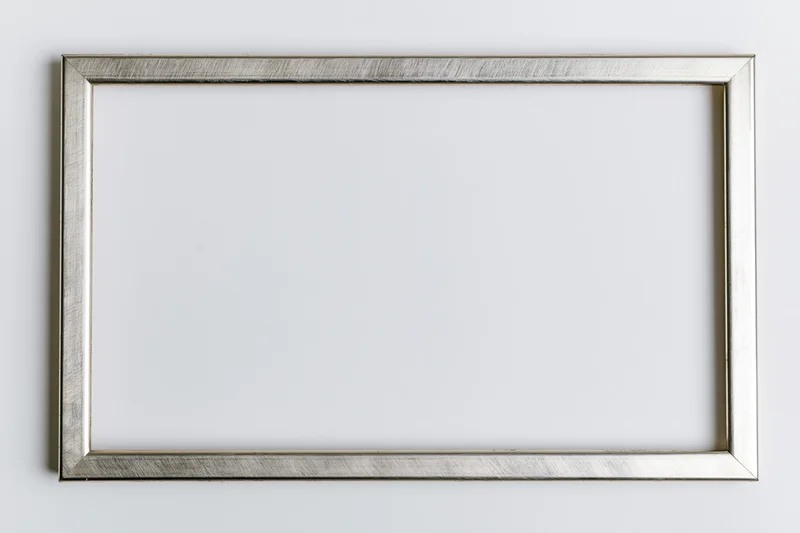 Silver metallic picture frame hanging on white wall with empty space for artwork
