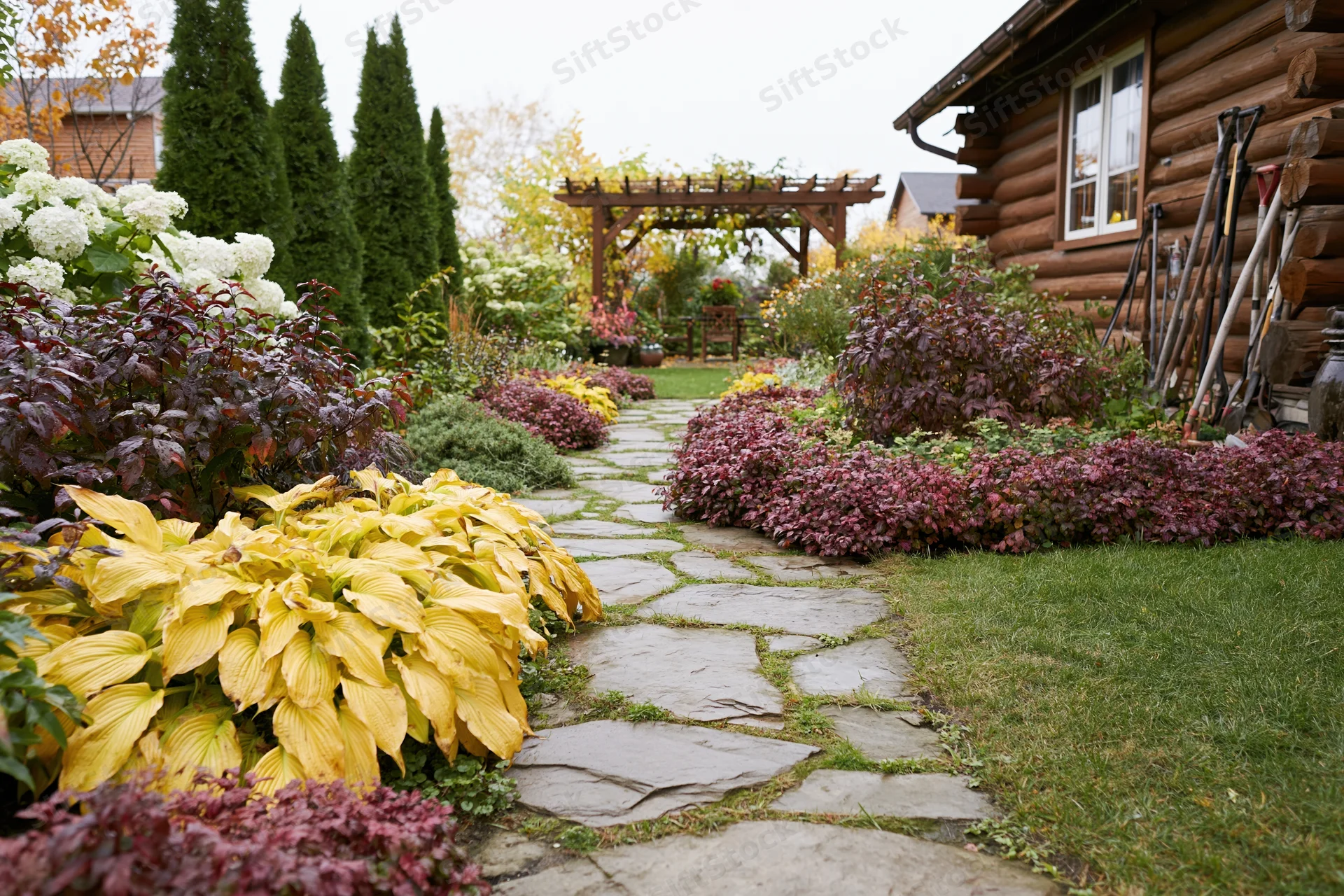 Stone path winding through colorful autumn garden beside log cabin