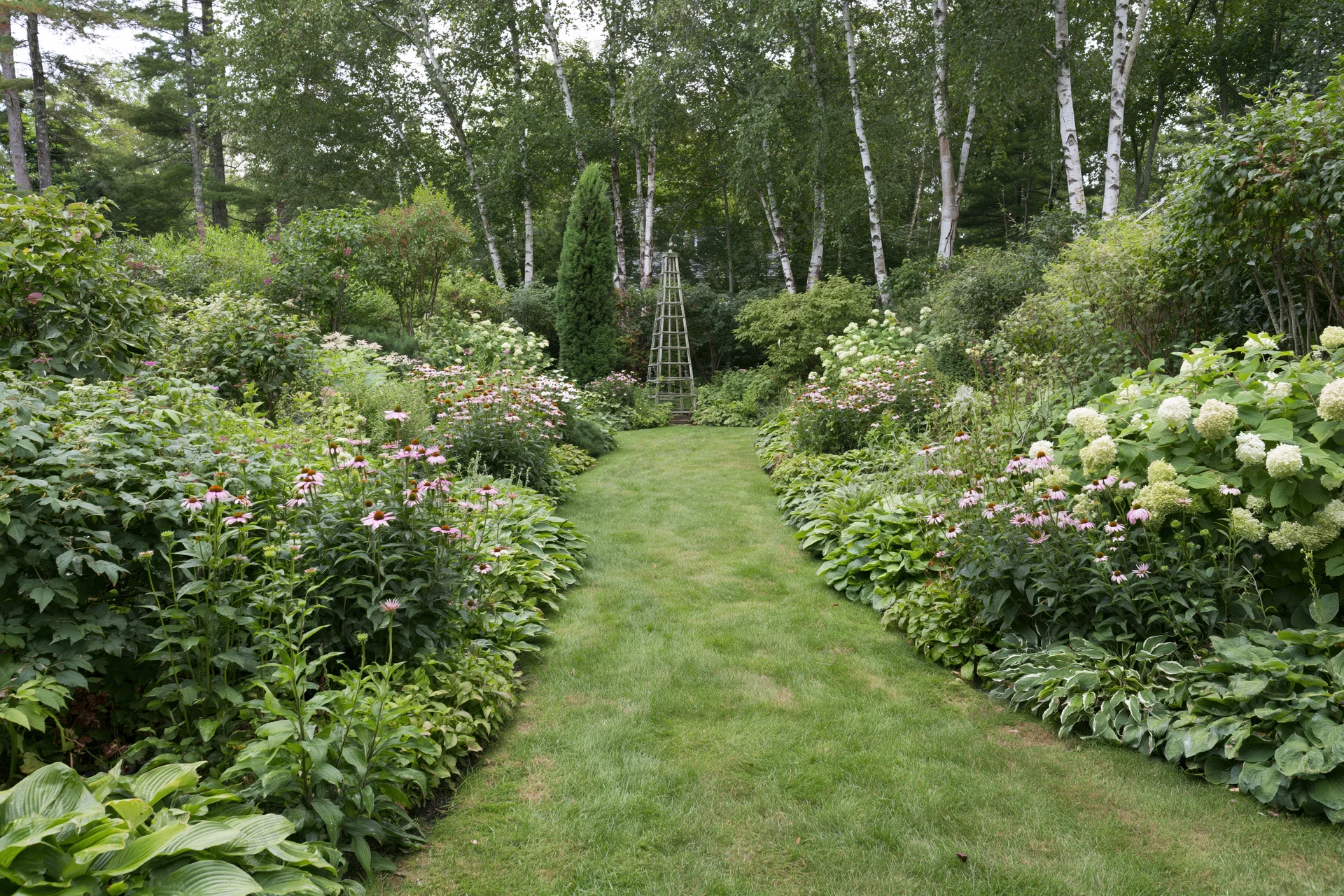 Grass path lined with blooming flowers and shrubs in a private garden