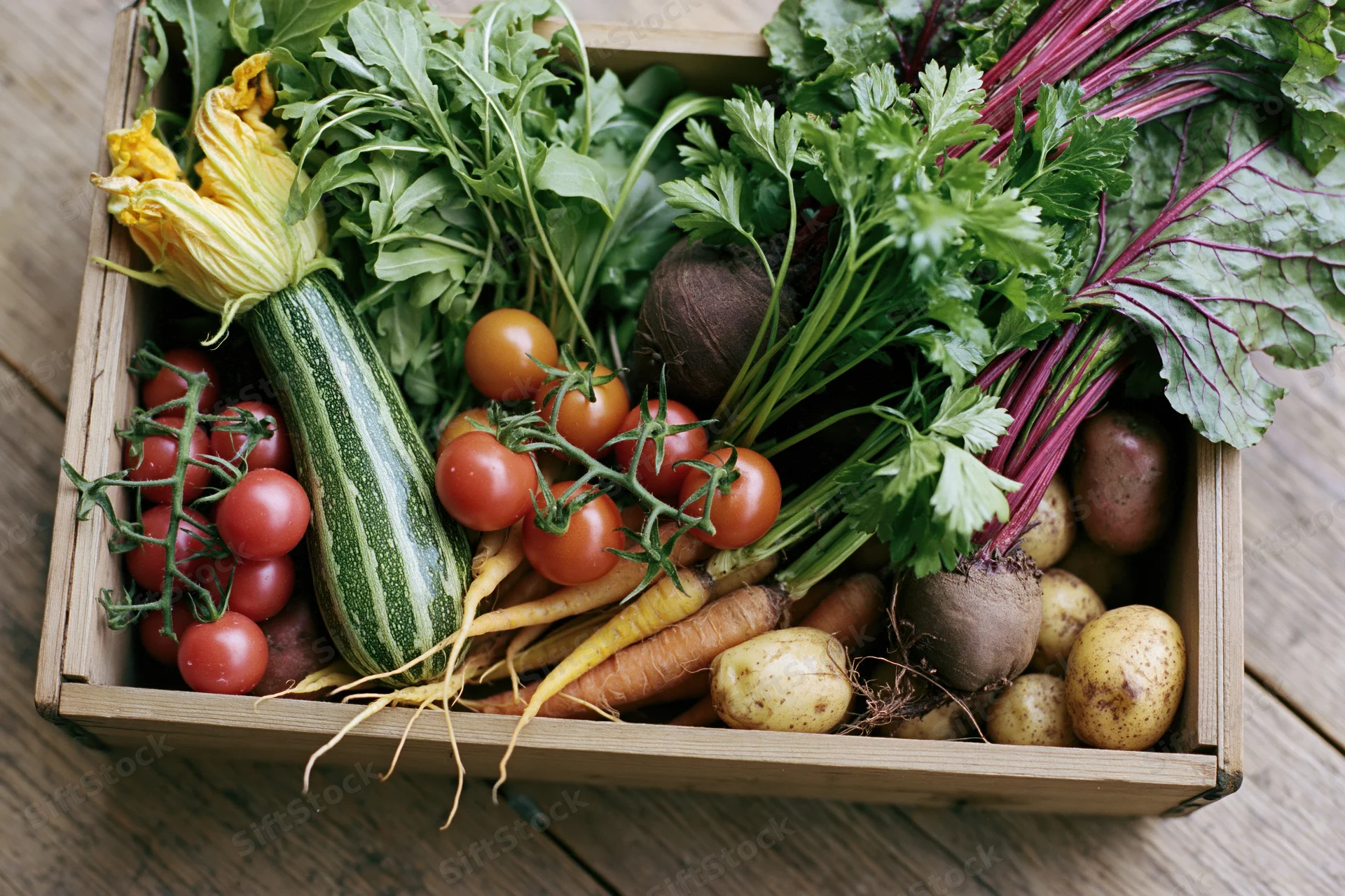 Wooden crate filled with fresh harvested vegetables on a wooden surface