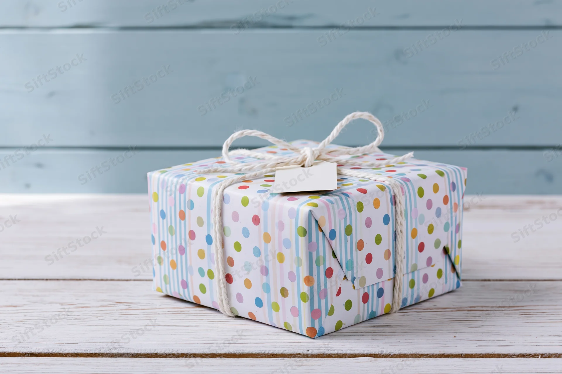 Wrapped gift box with polka dot paper and twine bow on wooden surface