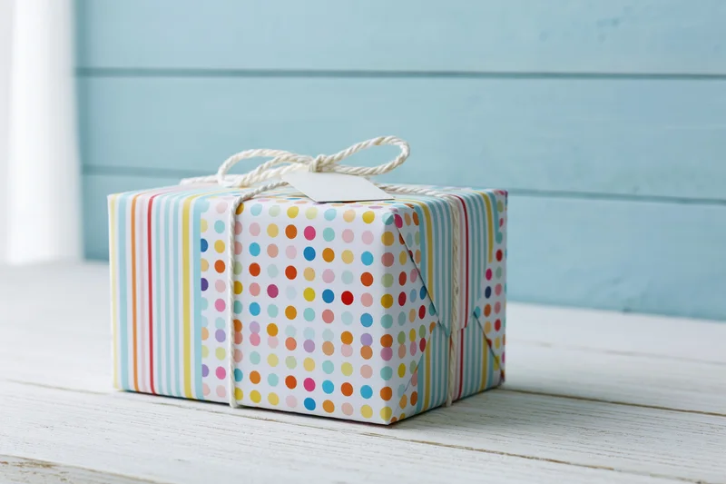 Wrapped gift box with polka dots and stripes on a white wooden table
